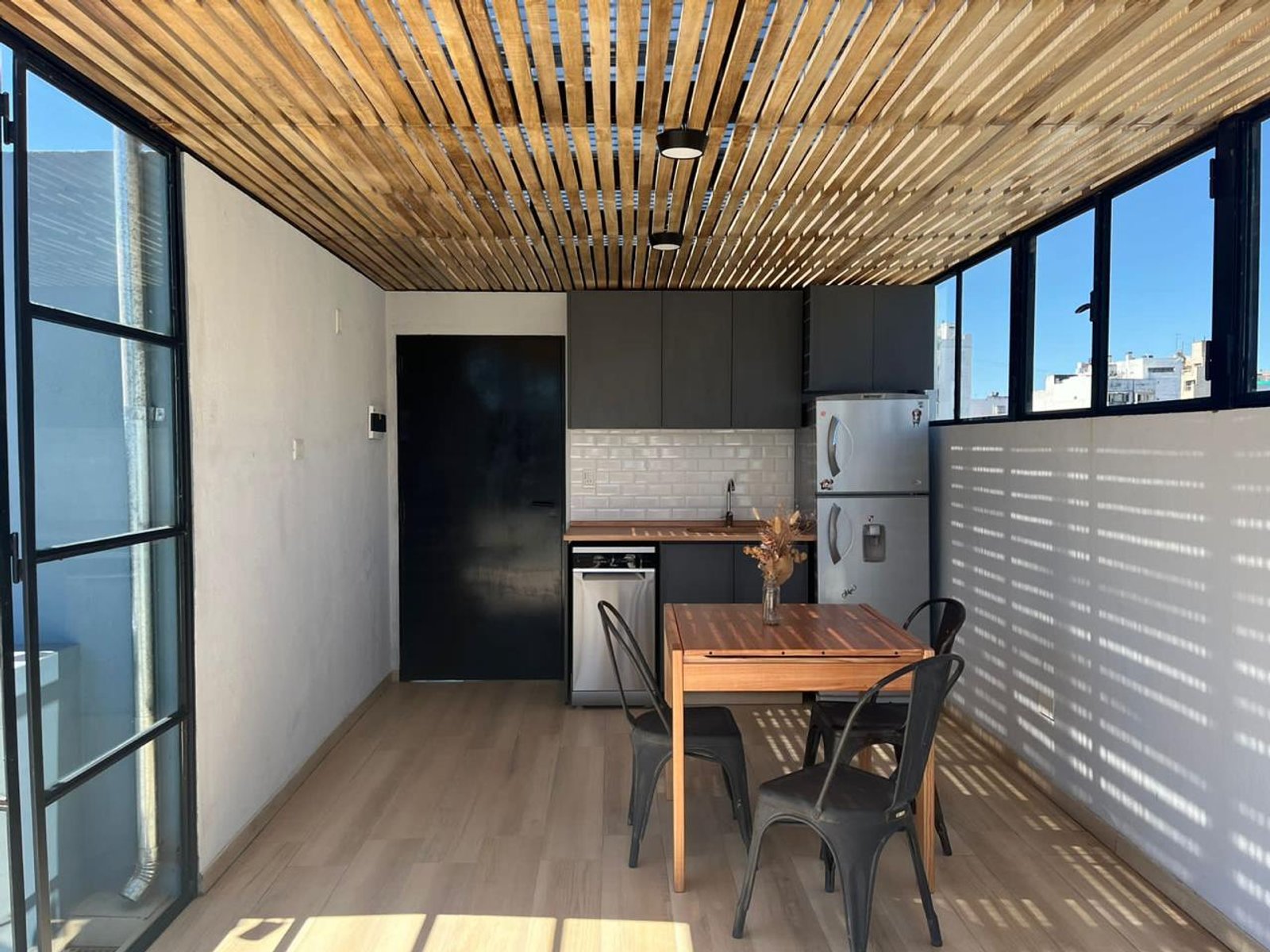 Sala de jantar semi-externa com teto de madeira e cozinha integrada — projeto Gorriti, por Estudio NET Arquitectura, em Gorriti 3768